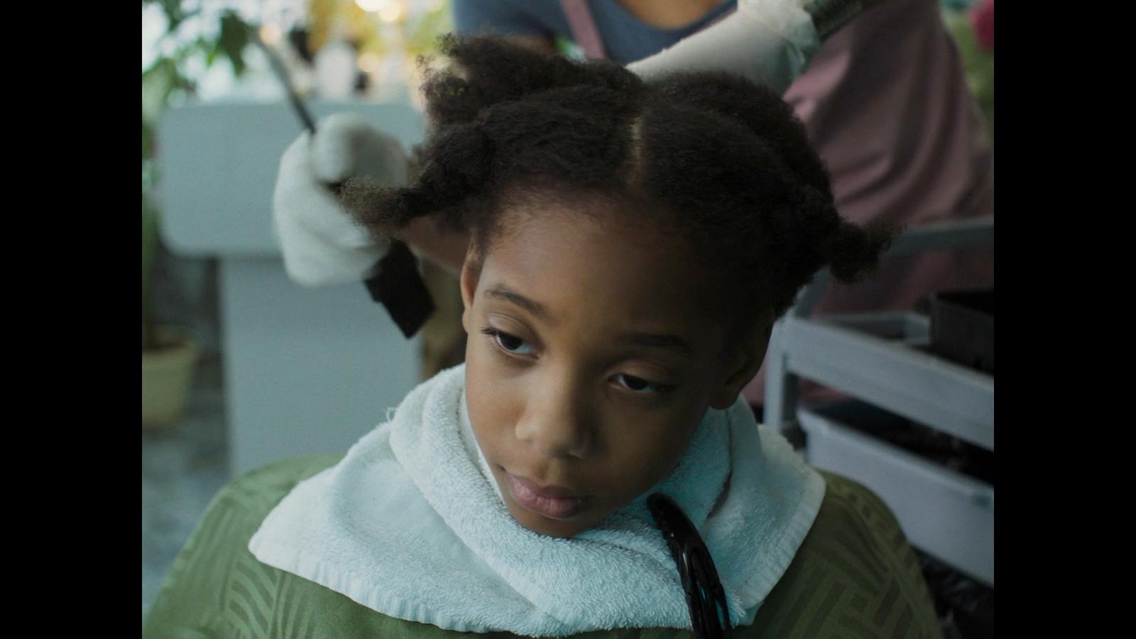 a young girl getting her hair styled by a hair stylist