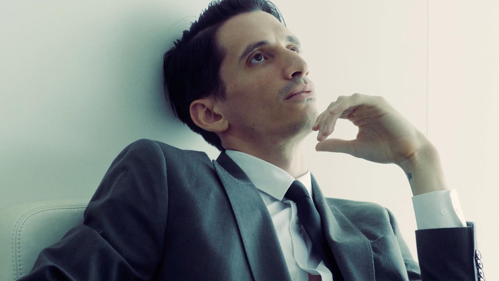 a man in a suit leaning against a wall