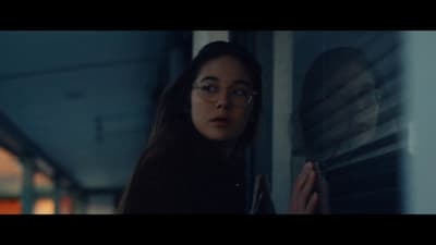 a woman wearing glasses looking out of a window