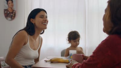 a woman sitting at a table next to a little girl