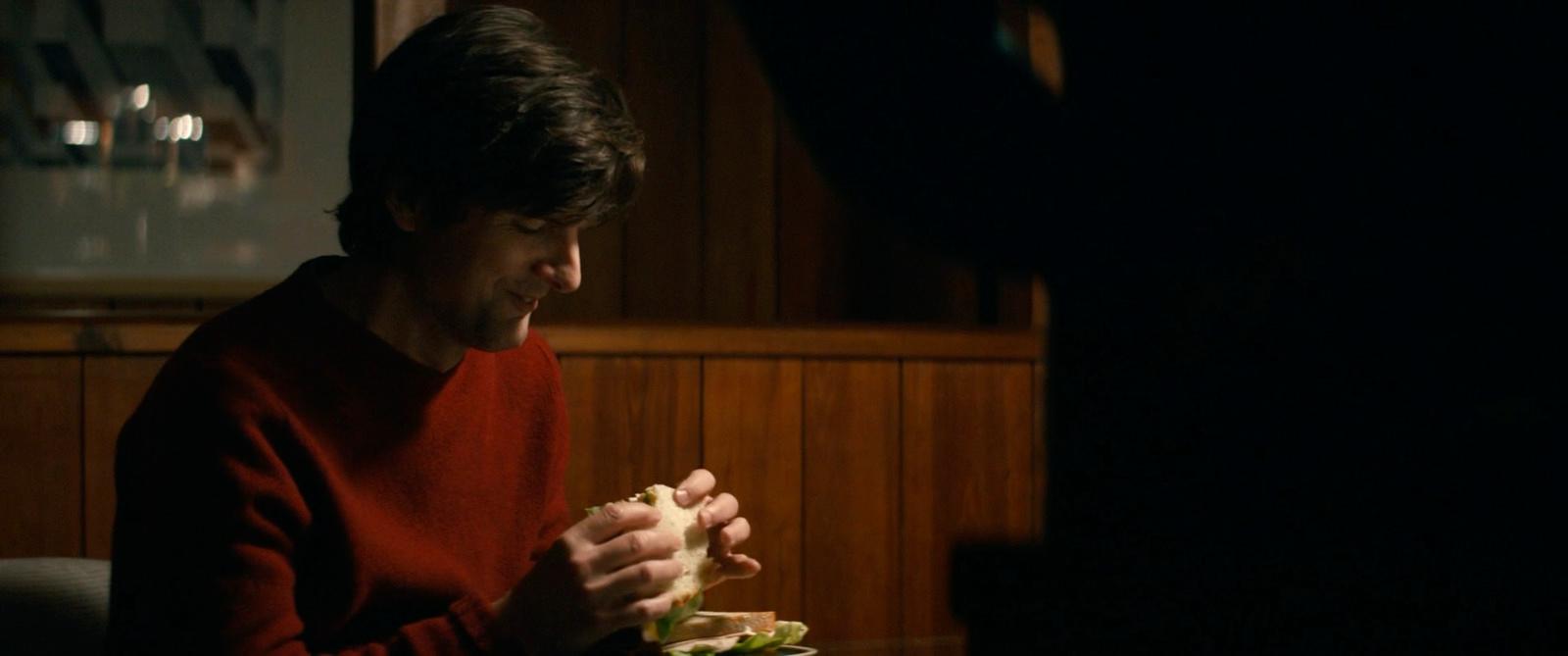 a man sitting at a table eating a sandwich