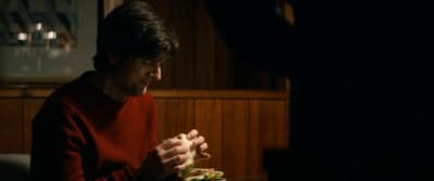 a man sitting at a table eating a sandwich