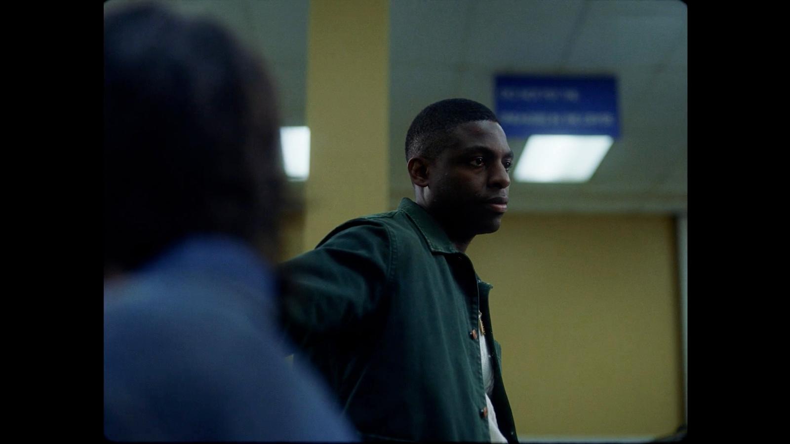 a man in a green jacket standing next to another man