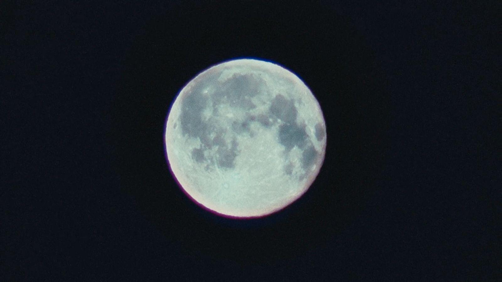 a full moon is seen in the dark sky
