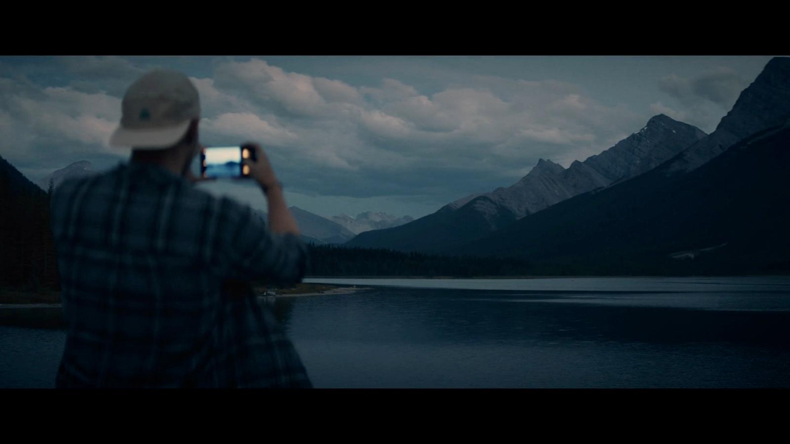 a man taking a picture of a mountain lake