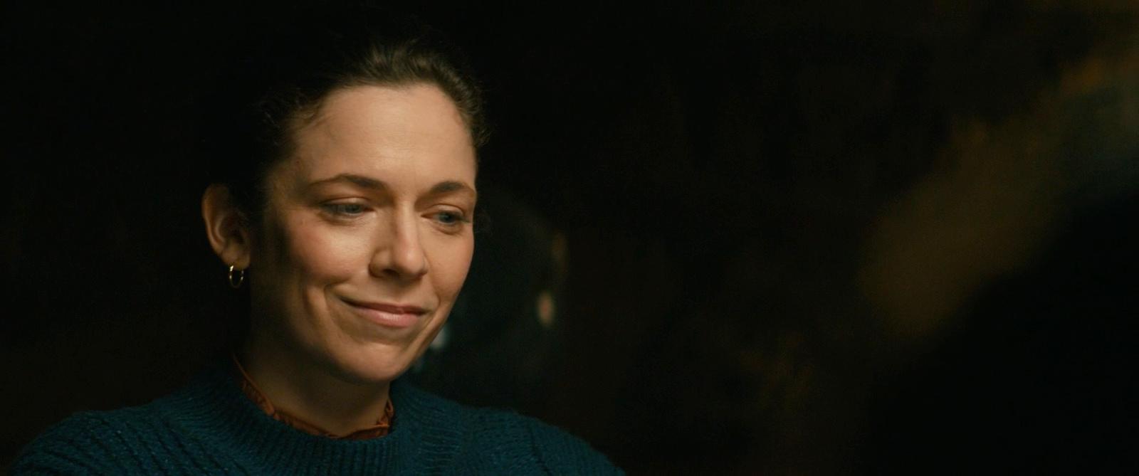 a woman in a green sweater smiling at the camera