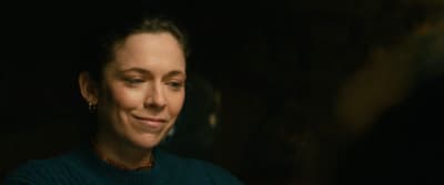 a woman in a green sweater smiling at the camera