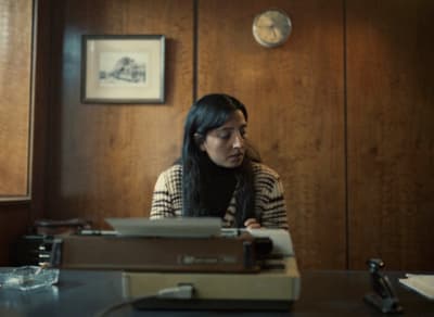 a woman sitting at a desk with a typewriter in front of her