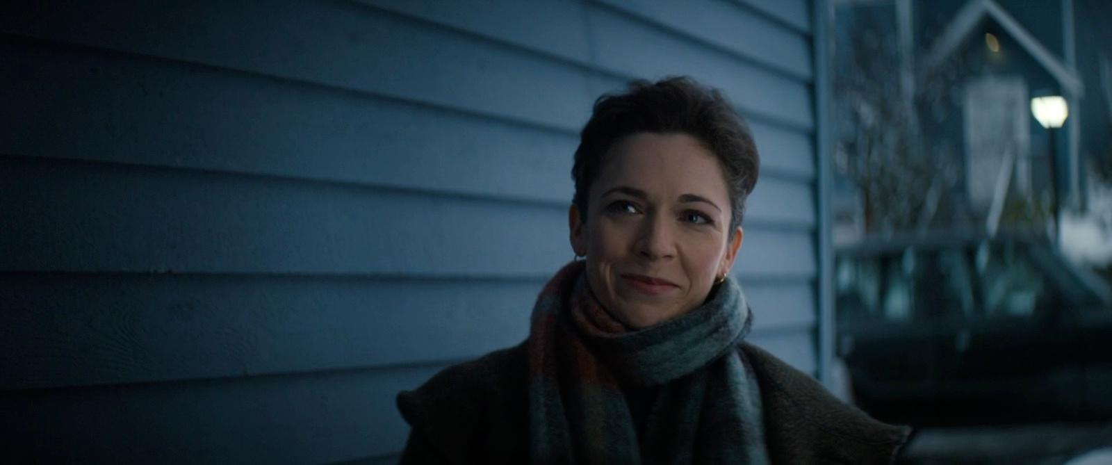 a woman standing outside of a house at night