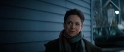 a woman standing outside of a house at night
