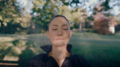 a woman with her eyes closed in a park