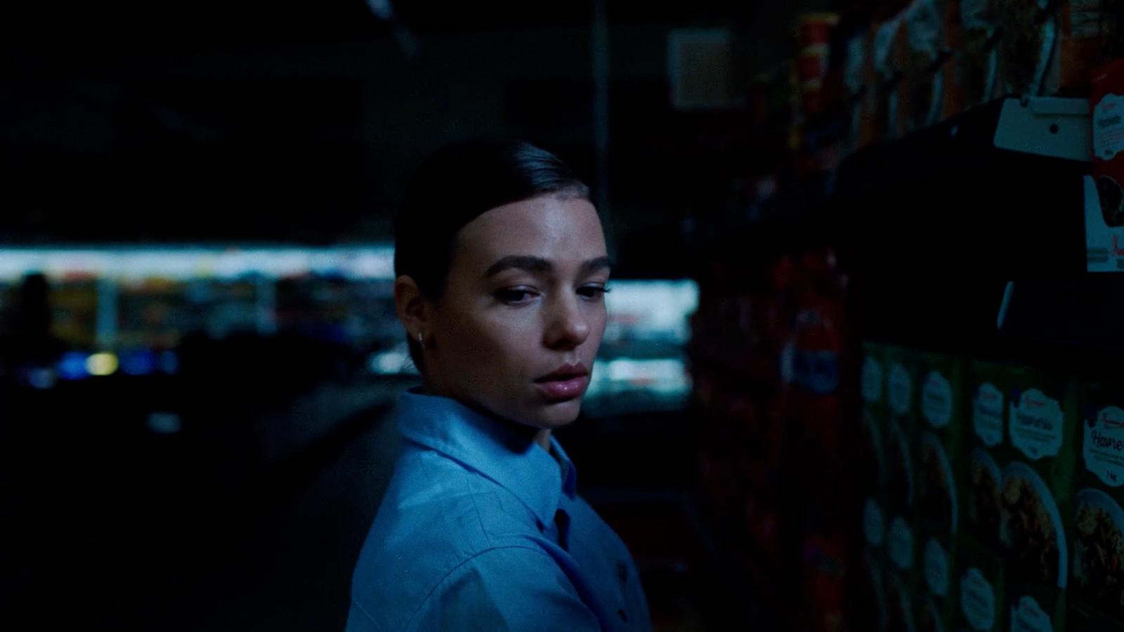 a woman in a blue shirt and tie in a dark room