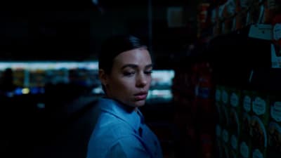 a woman in a blue shirt and tie in a dark room