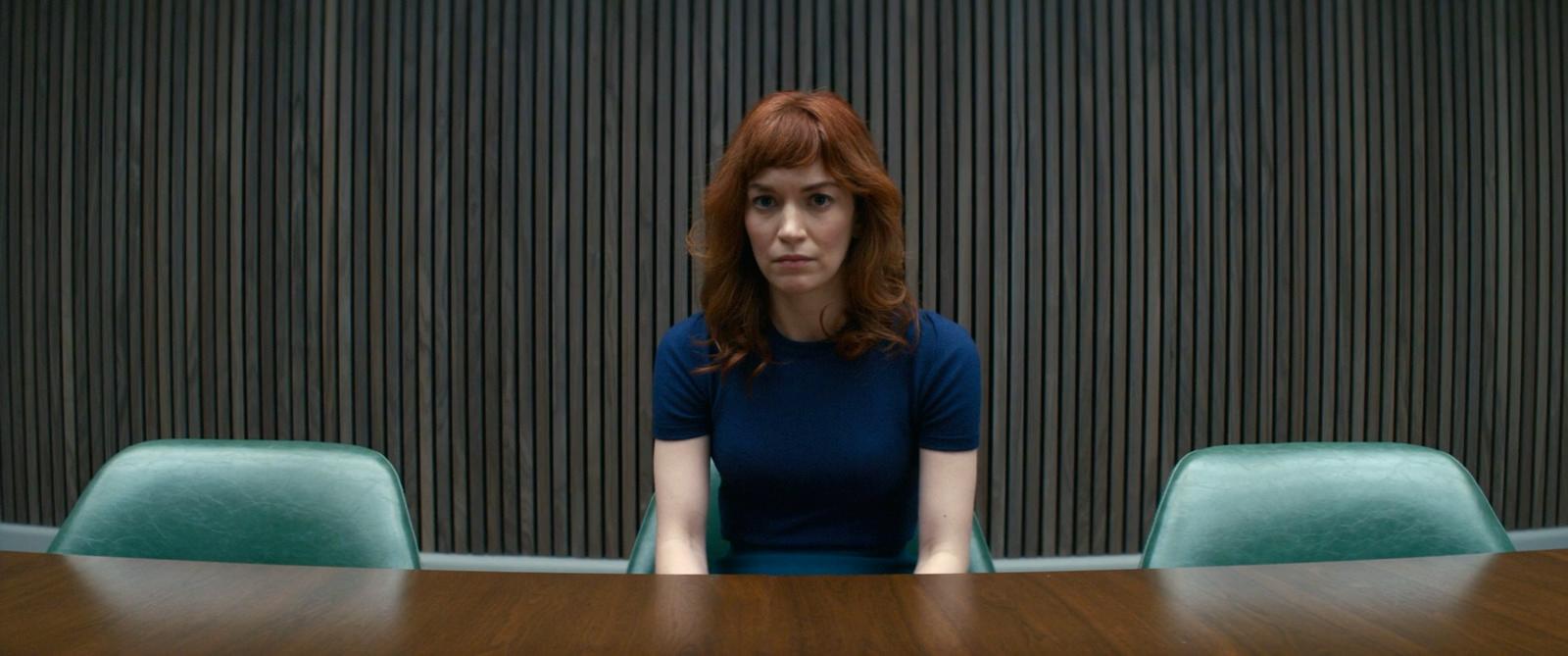 a woman sitting at a table in front of a wall