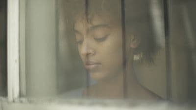 a woman looking out of a window with her eyes closed
