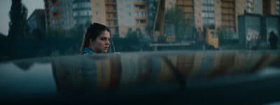 a woman sitting on a bench in front of tall buildings