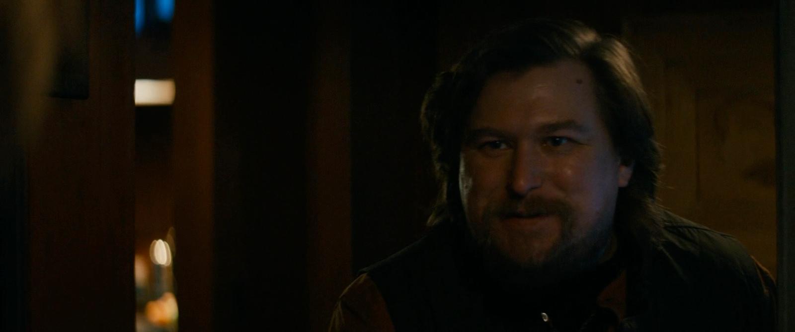 a man with long hair and a beard in a dark room