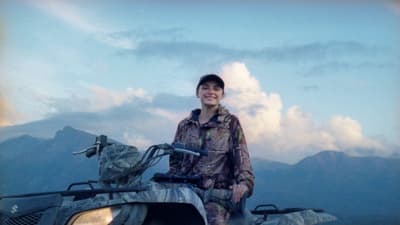 a woman standing next to an atv with mountains in the background