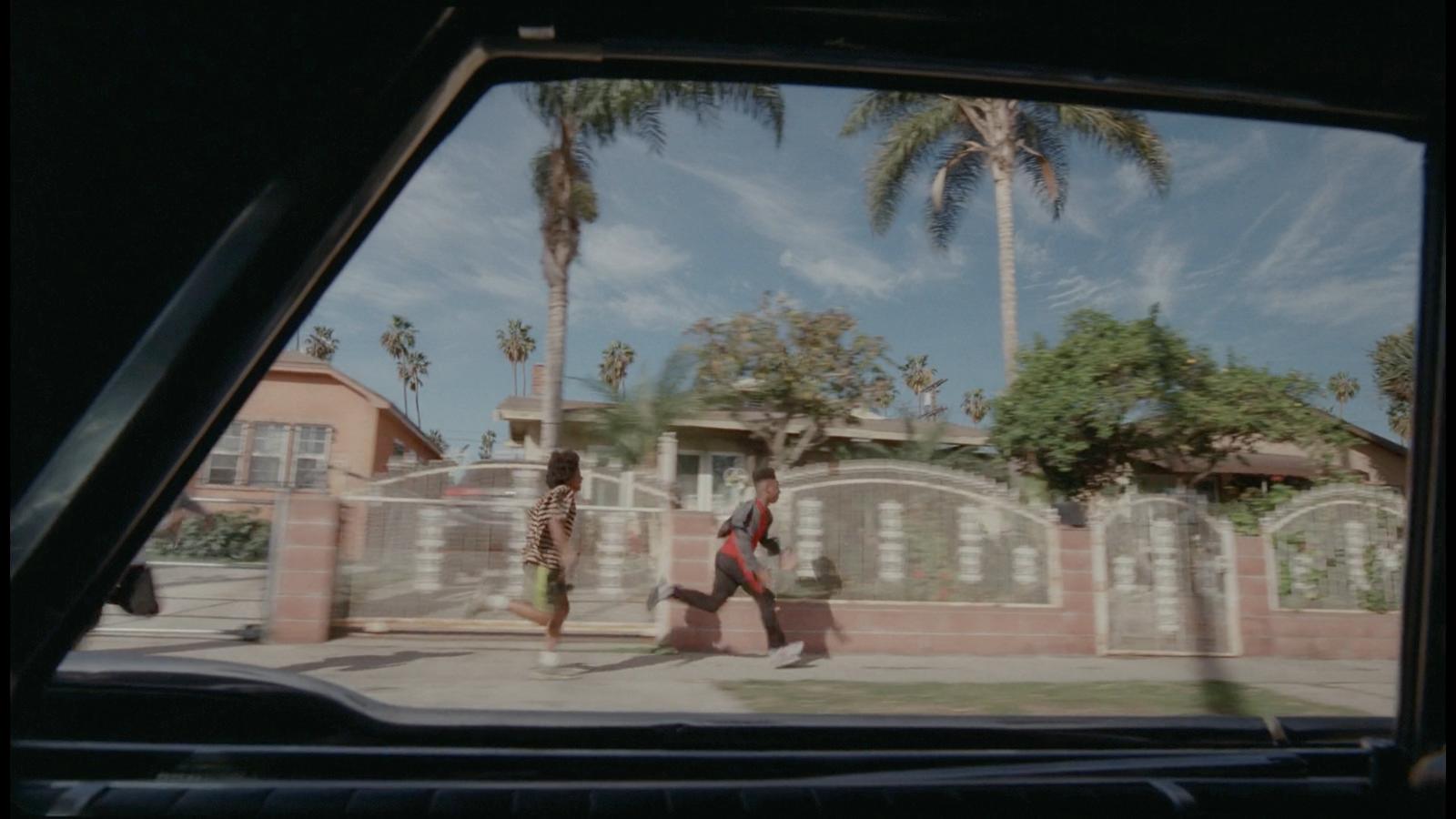 a man walking down a street next to a palm tree