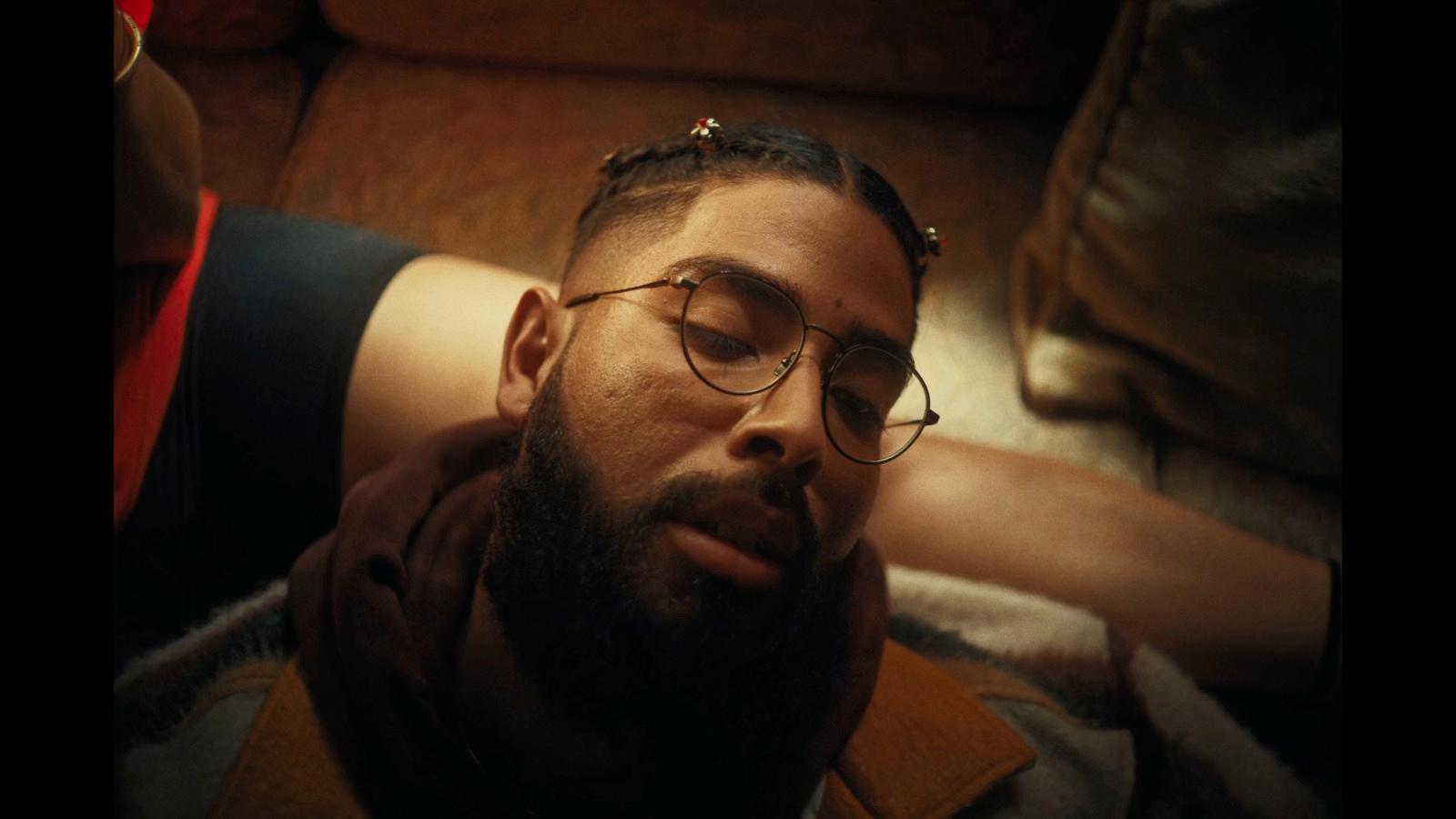 a man with glasses laying on a couch