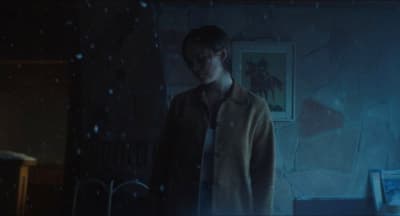a man standing in a room with a painting on the wall