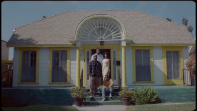 a man and a woman standing in front of a yellow house