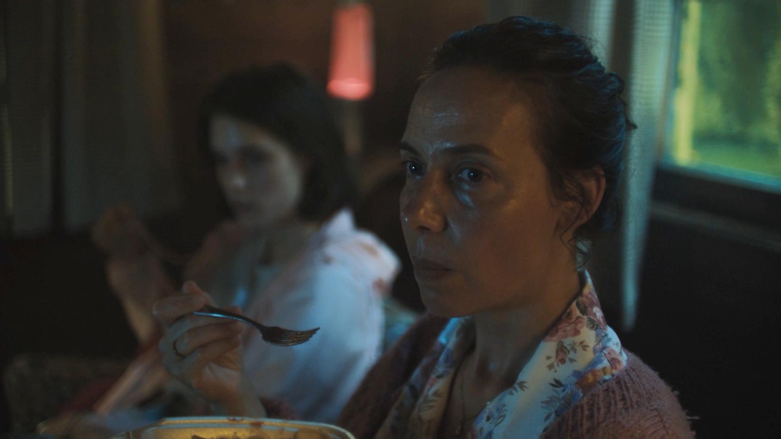 a woman sitting at a table with a bowl of food