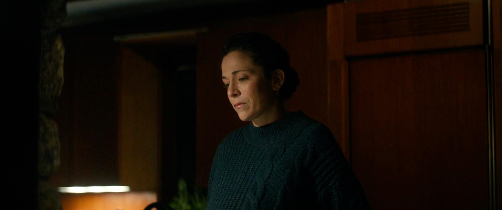 a woman standing in a dark room next to a lamp