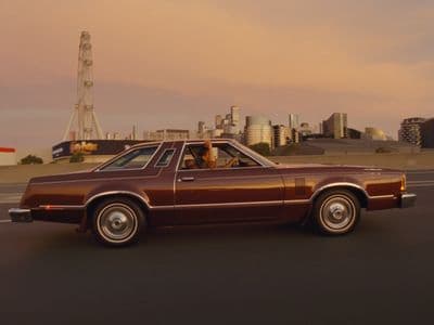 a brown car driving down a street next to a tall building