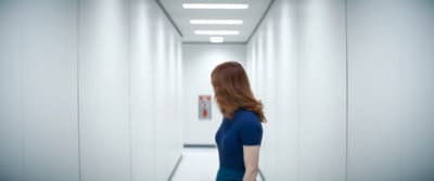 a woman in a blue dress walking down a hallway
