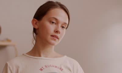 a woman in a t - shirt is staring at the camera