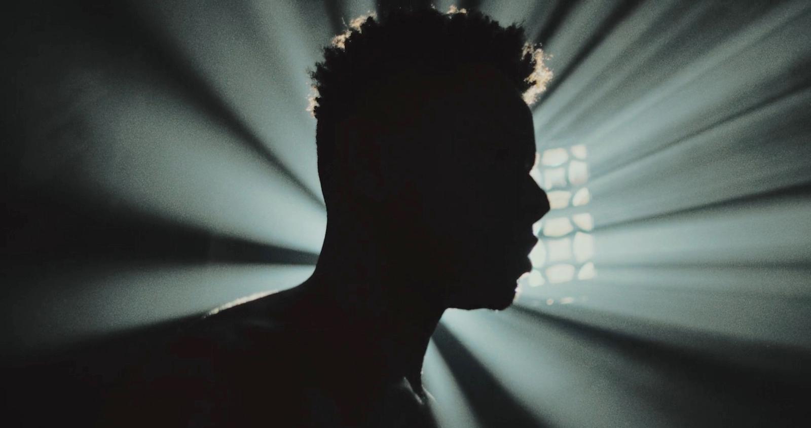 a silhouette of a man in front of a spotlight