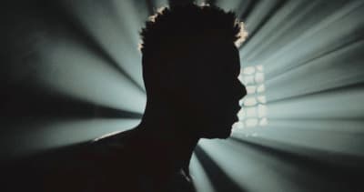 a silhouette of a man in front of a spotlight