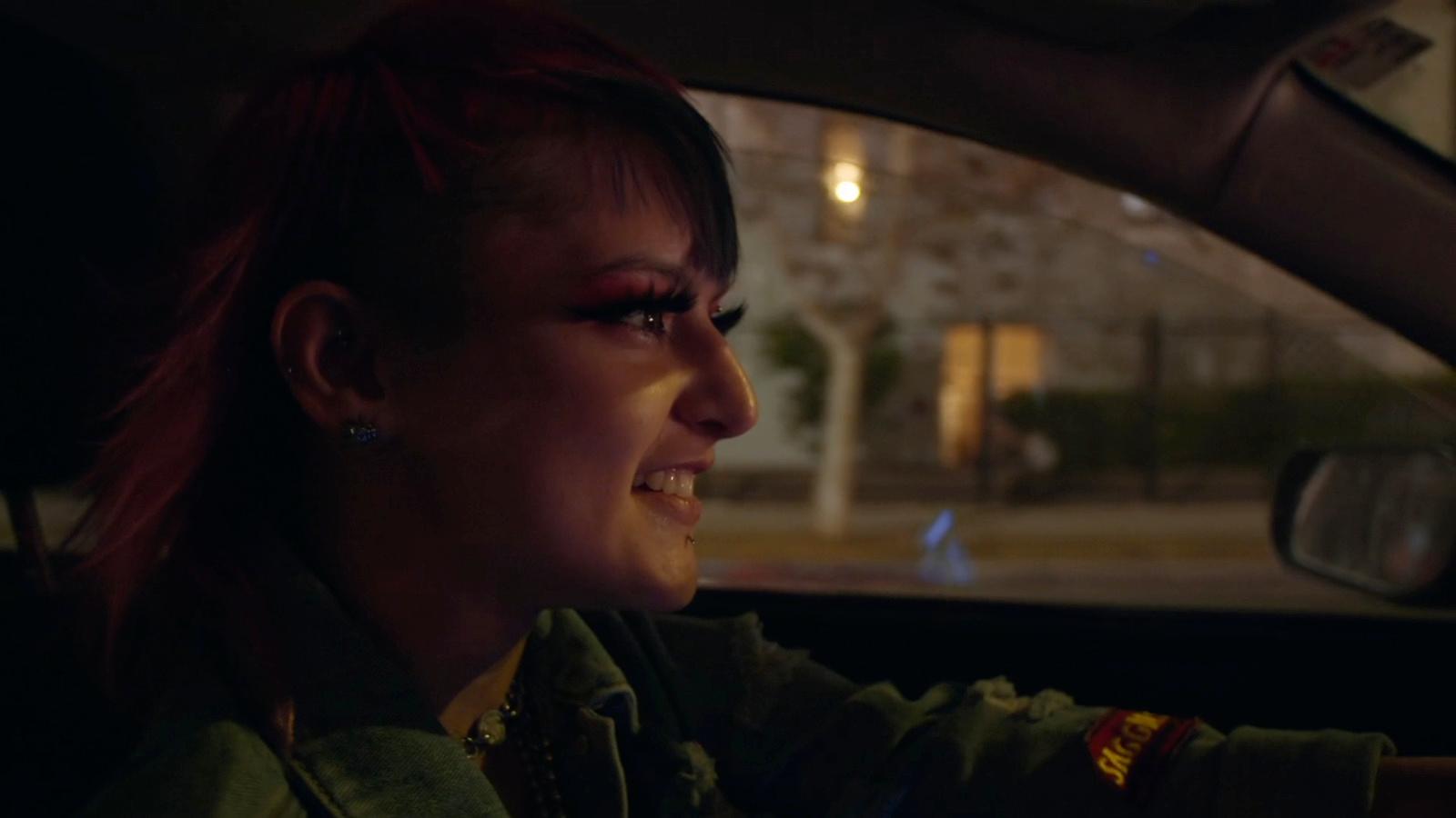 a woman with red hair driving a car at night