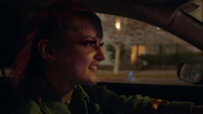 a woman with red hair driving a car at night