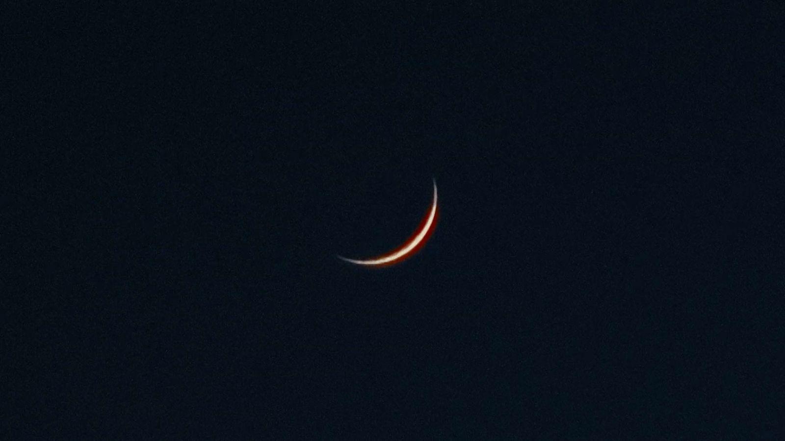 a crescent moon is seen in the dark sky