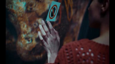 a woman holding a piece of paper in front of a painting