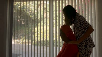 a woman standing next to a man in front of a window