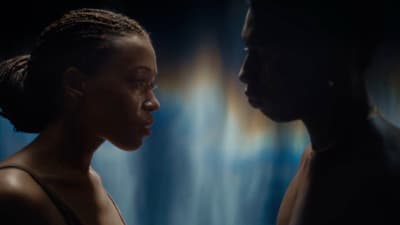 a woman standing next to a man in a dark room