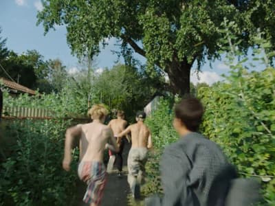a group of men walking down a street next to a lush green forest