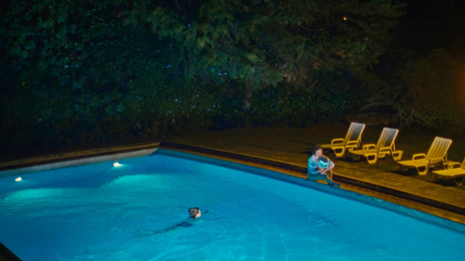 a person sitting in a swimming pool at night