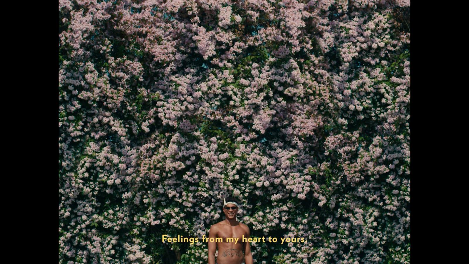 a man standing in front of a wall of flowers