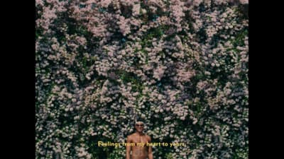 a man standing in front of a wall of flowers