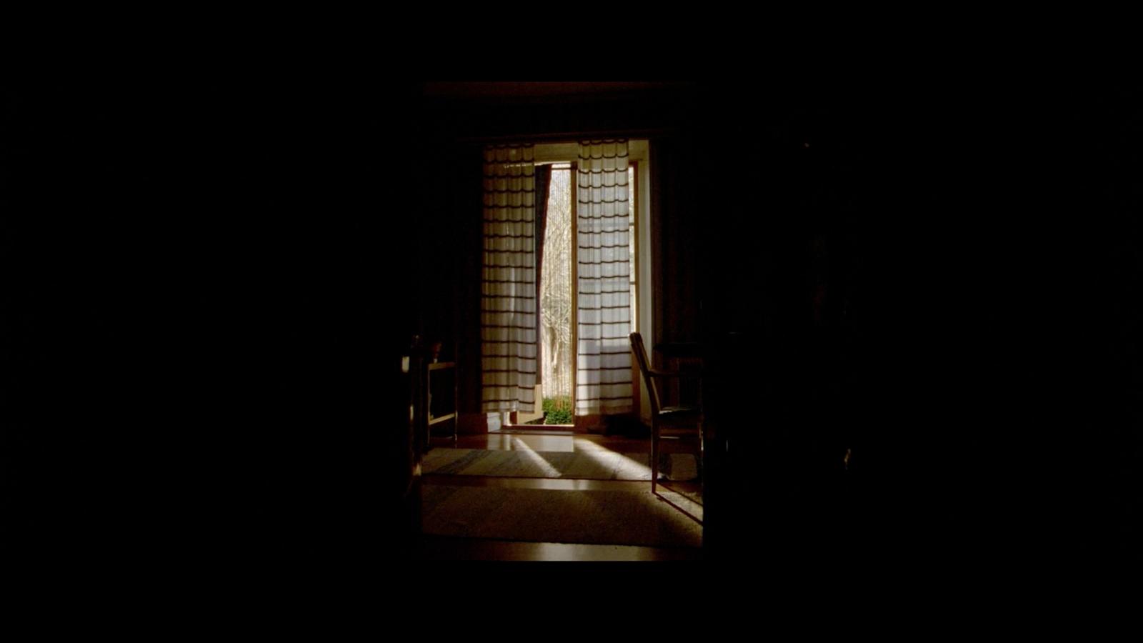 a dark room with a window and a chair