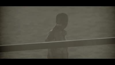 a young boy standing on a beach next to a body of water