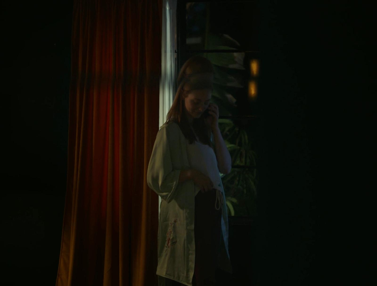 a woman standing in front of a window talking on a cell phone