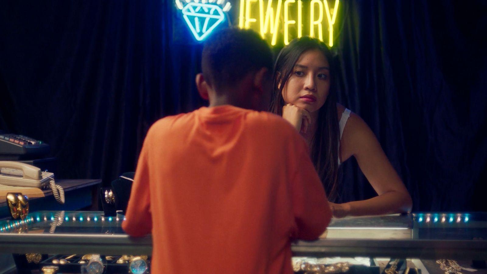 a man and a woman standing in front of a neon sign