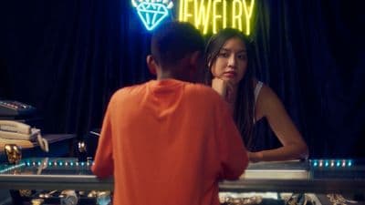 a man and a woman standing in front of a neon sign