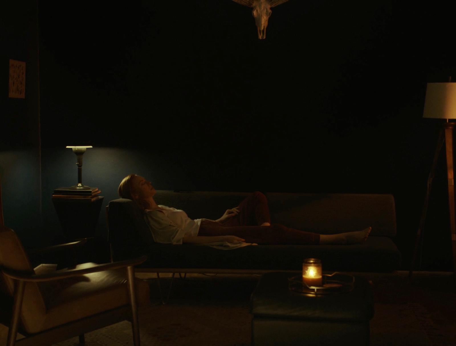 a woman laying on a couch in a dark room