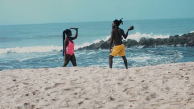 a couple of women standing on top of a sandy beach